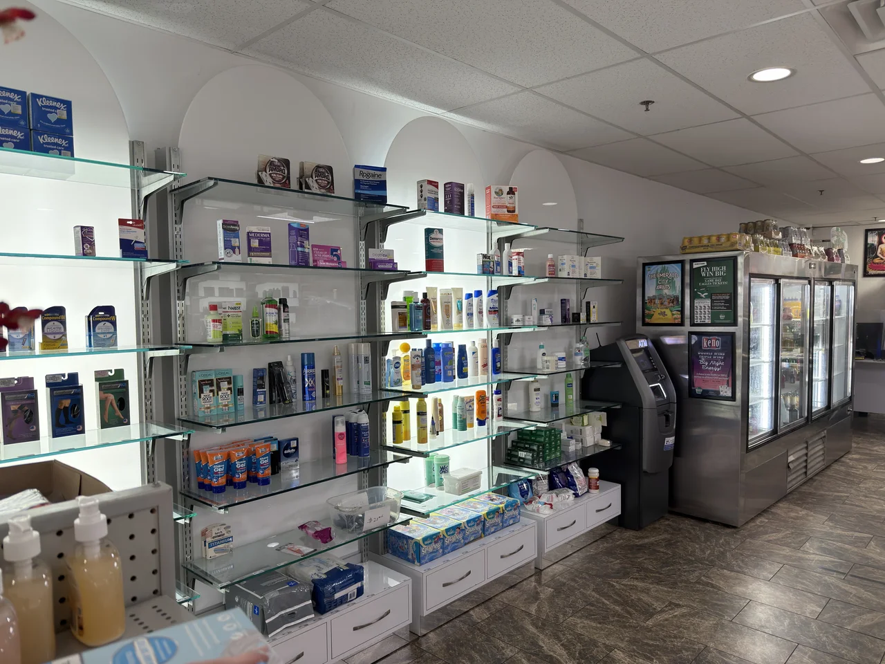 Pharmacy shelves stocked with personal care products beside refrigerated displays